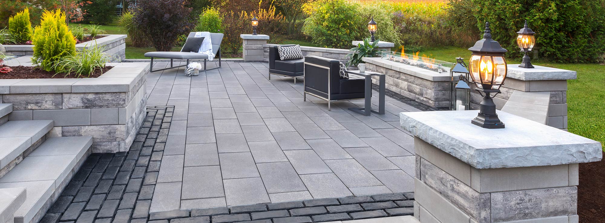 An area with a fire pit, chairs, and retaining walls on pavers.