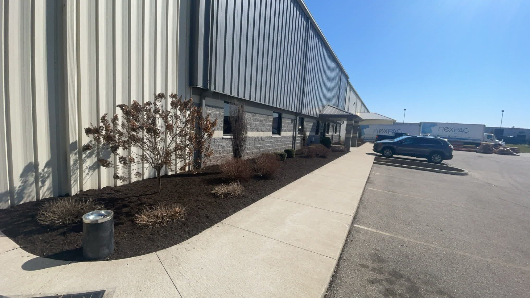 Commercial building with freshly mulched landscape beds, pruned bushes, and clear walkways after fall cleanup services.